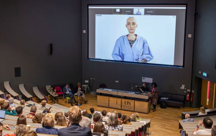 Sophia the first robot citizen on a large live screen in Jubilee Lecture Theatre