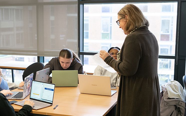 Students studying at their desk next to their tutor