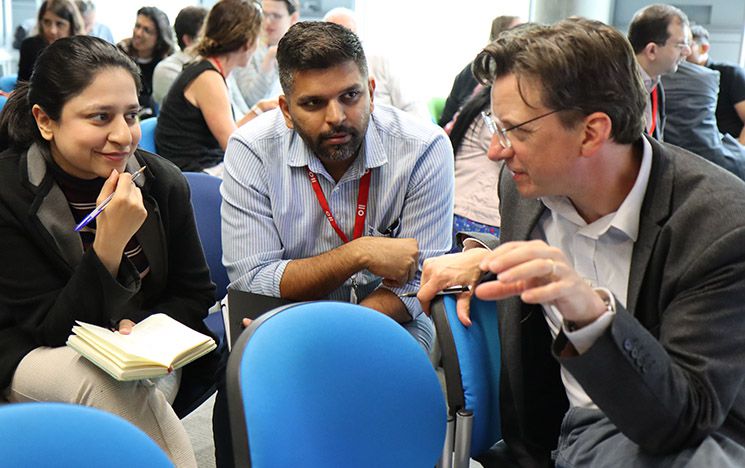 Three academics having a discussion sitting on chairs in a semi-circle