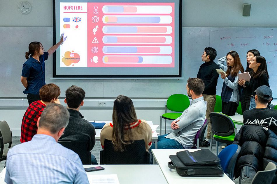 Students looking intrigued, gathered round a white board presentation with notepads