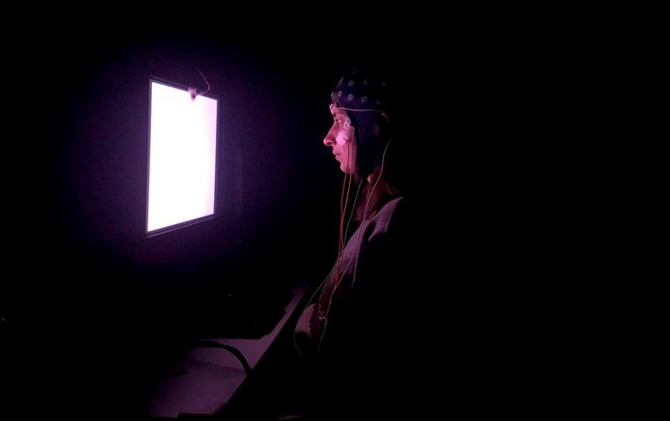 showing screen in darkened room with person wearing EEG cap