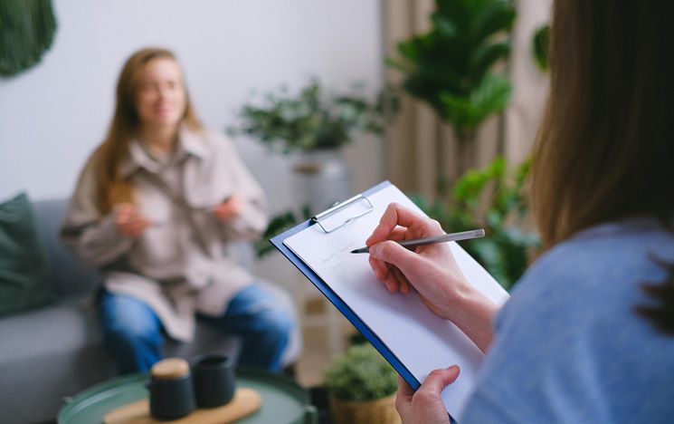 person interviewing another person with a clipboard like a clinical interview