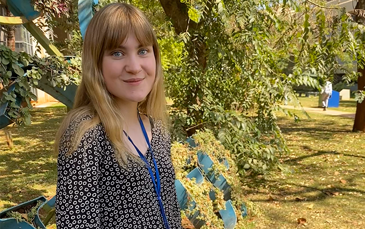 A student in a black and white shirt with a green space in the background.