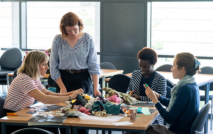 A group of women gathered around a table of materials