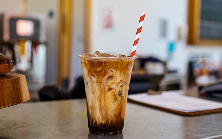 An iced coffee sitting on a silver countertop.