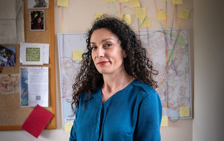 Dr Sarah Scuzzarello standing in front of a pinboard and a map labelled with strings leading to post-it notes