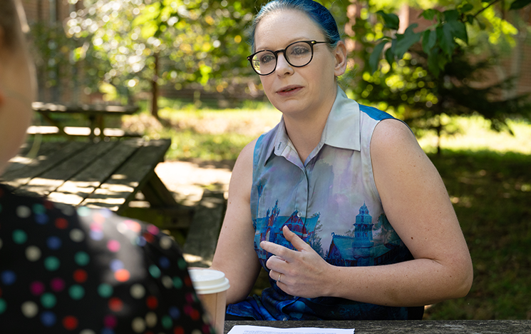 Victoria Grace Richardson-Walden talking to an interviewer, sitting outside on a picnic bench.