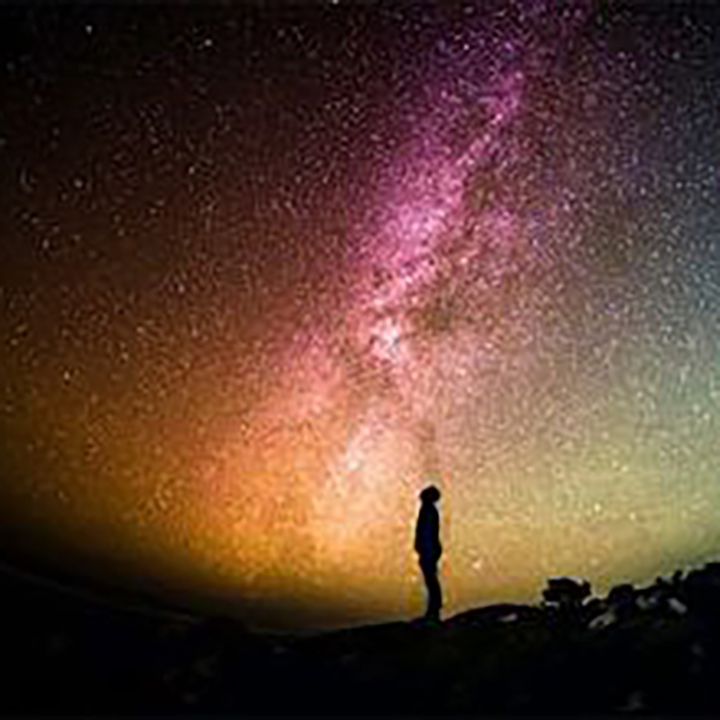 Figure looking into colourful night sky