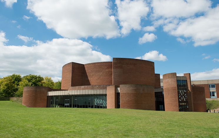 Curved red brick building with grass in front