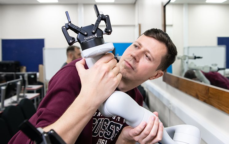 Student examining a robotic arm