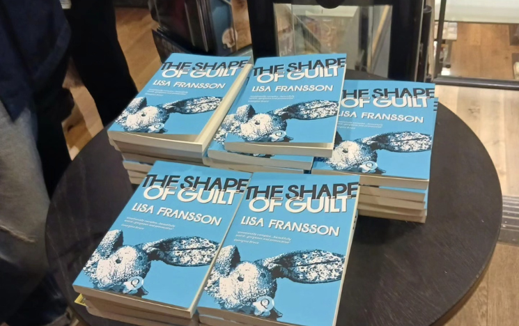 Stacks of Lisa Fransson's book The Shape of Guilt on a table.