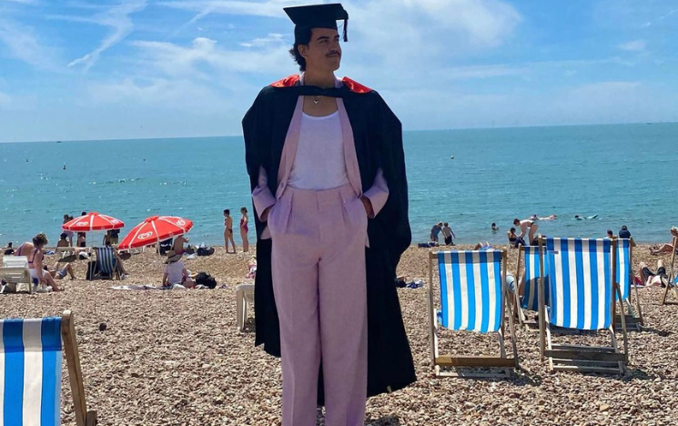Pablo Santana posing in his graduation gown on Brighton Beach.