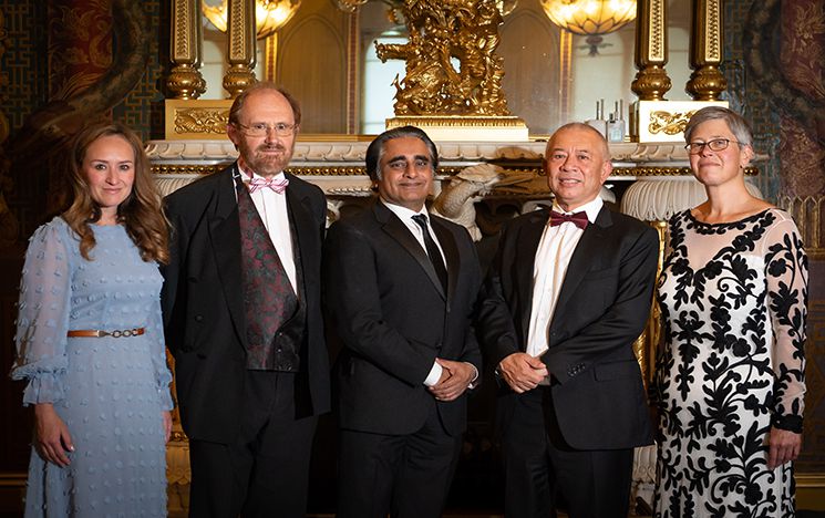 Group photo of Peter Bennett with four other people standing in front of an ornate fireplace at the Royal Pavilion and smiling