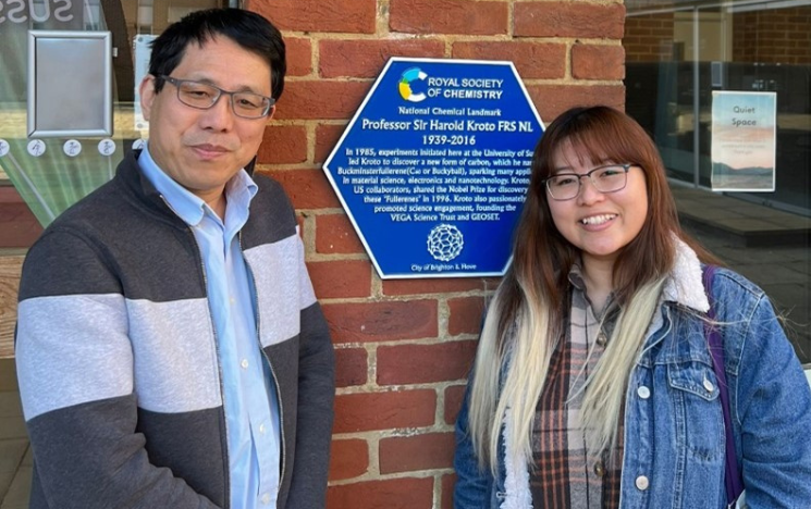 Huyen Le standing next to Dr. Qiao Chen, her Masters project supervisor, in front of the Professor Sir Harry Kroto FRS NL Chemical Landmarks blue plaque on campus.