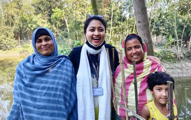 Tanjila Mazumder Drishti standing with two female fish farmers in rural Bangladesh.