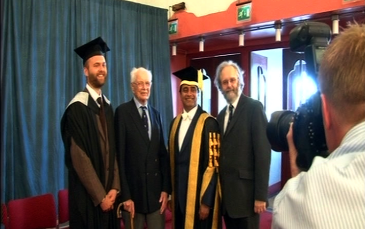 Tom Heritage stood with his father and grandfather and Chancellor Sanjeev Bhaskar OBE as the University photographer takes a photograph.