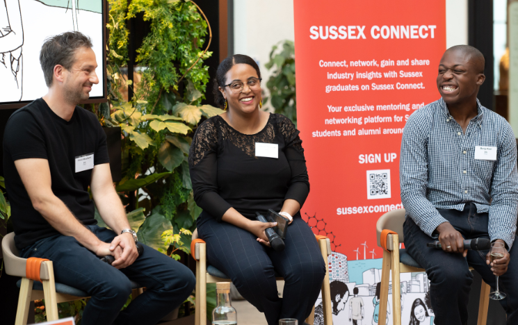 Sussex Alumni Omid Moallemi, Emnet Tiruneh and Benjy Kusi sat facing the crowd and smiling at a recent graduate event in London.