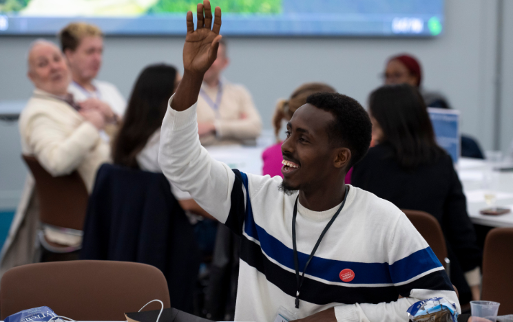 An attendee raising their hand at a Make it Happen networking event in the Student Centre.