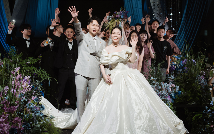 Candice and Yifan with their wedding guests surrounded by flowers.