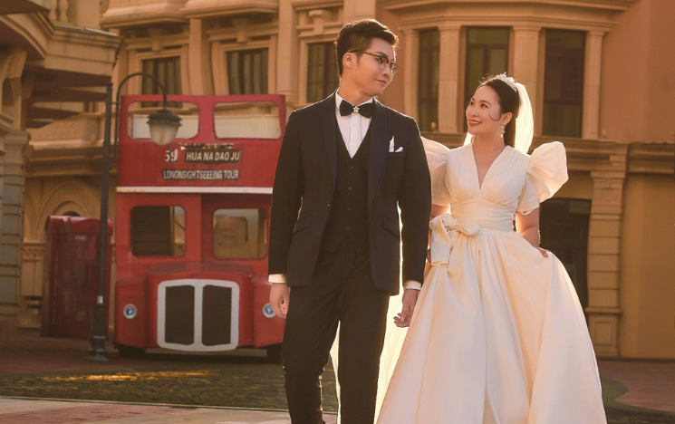 Yangyang Pu and YuChang Hsieh posing in formal clothing with a London-style red bus behind them.