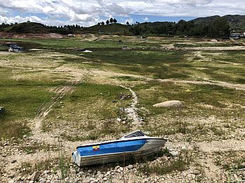 Guatape - blue and white boat laying on it's side in a field. Rolling green hills in the background.