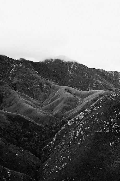 Black and white mountains with some clouds near the peaks