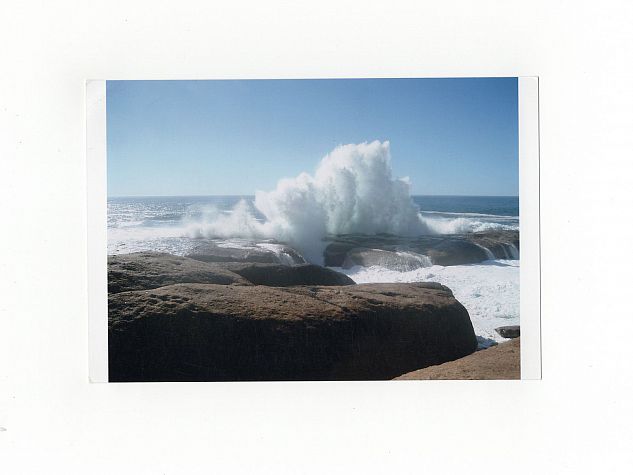 A wave crashes into rocks by the sea