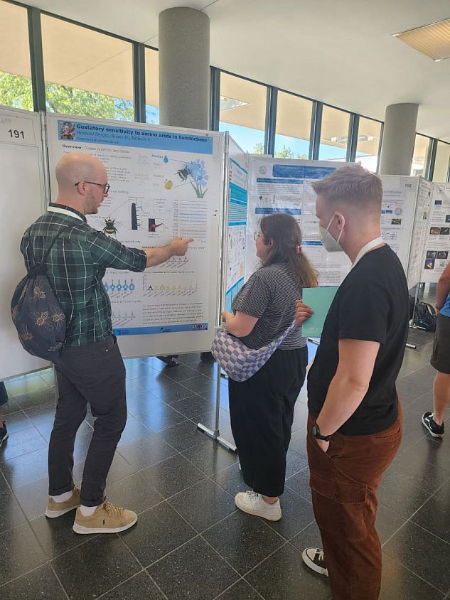 Sergio is explaining his poster to two attendees at ICN