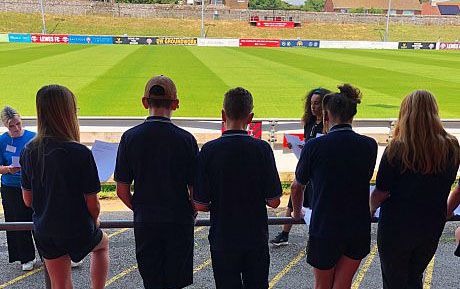 Erin James leads a chant with young people at a football ground