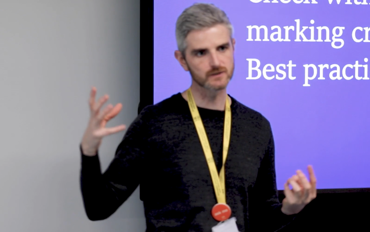 Member of teaching staff stood in front screen teaching students