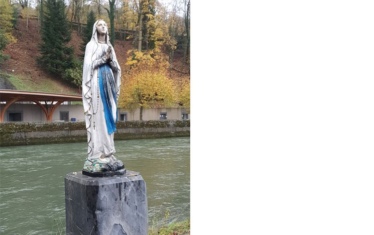 Statue of Our Lady next to the Gave river, with the baths in the background