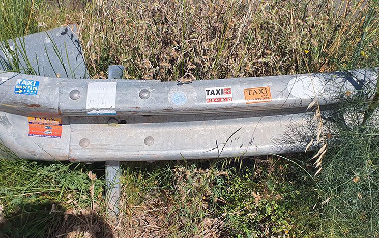 A photo of a road barrier, with taxi service stickers placed across it