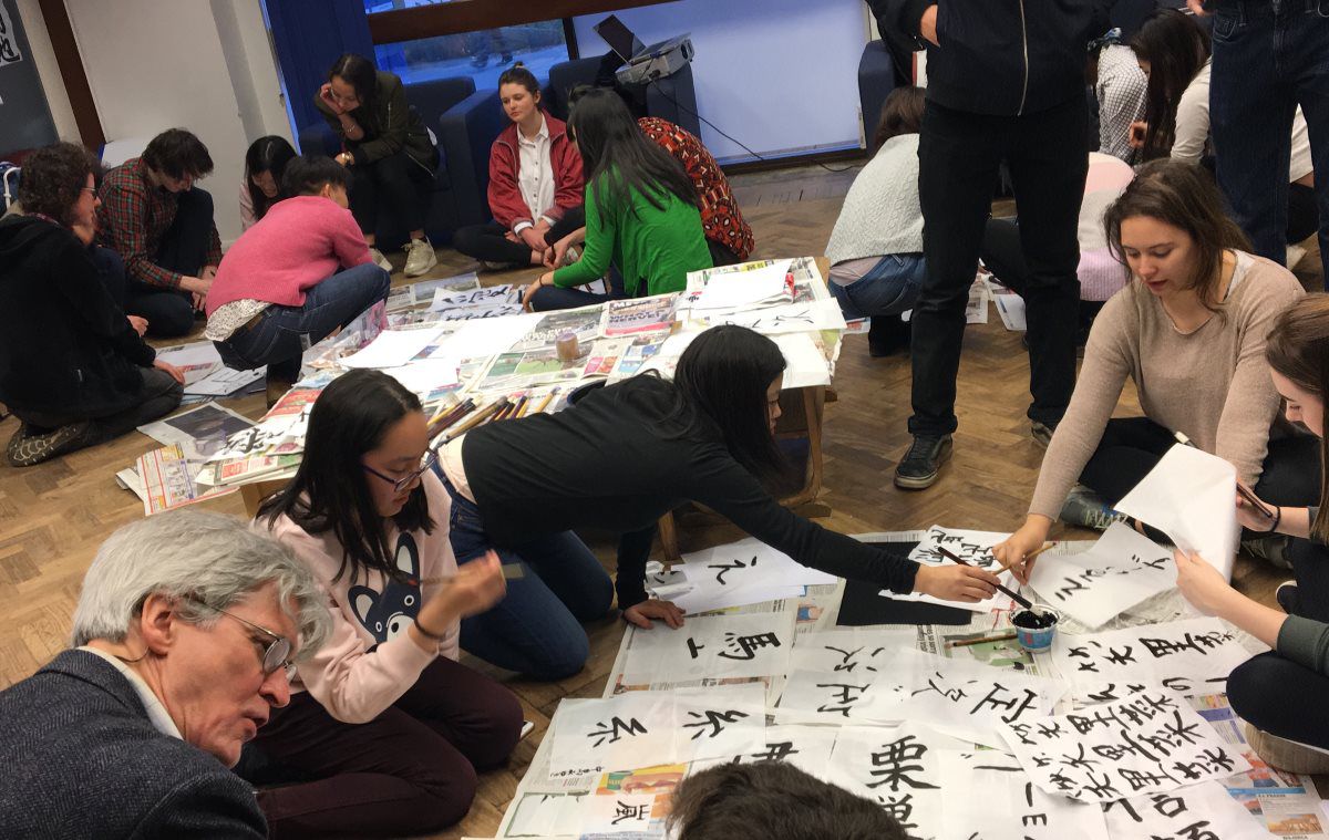 students on floor painting large calligraphy