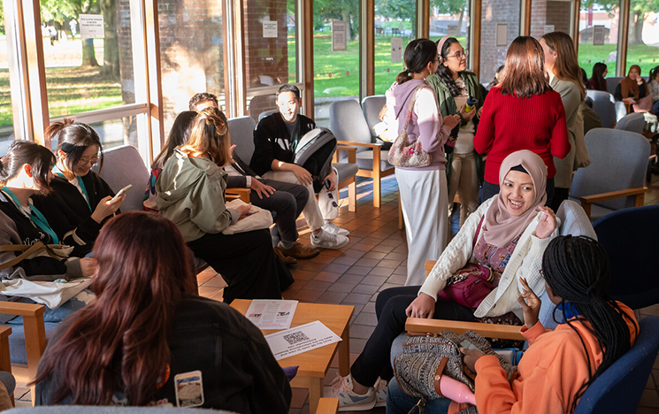 Students sitting in a cafe and speaking to each other at a welcome event.