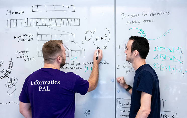 Informatics students writing on a whiteboard