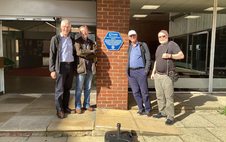 Three alumni standing by the Sir Harry Kroto blue plaque on campus
