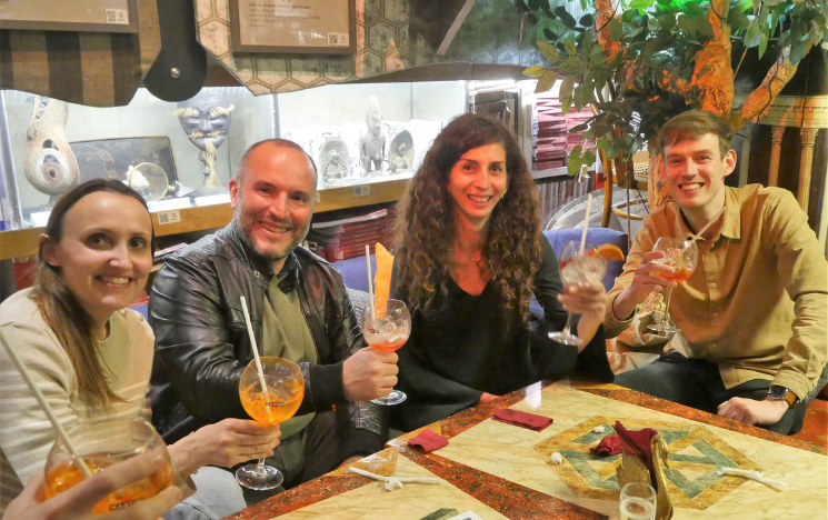 Four alumni sitting at a table holding drinks in a restaurant in Rome