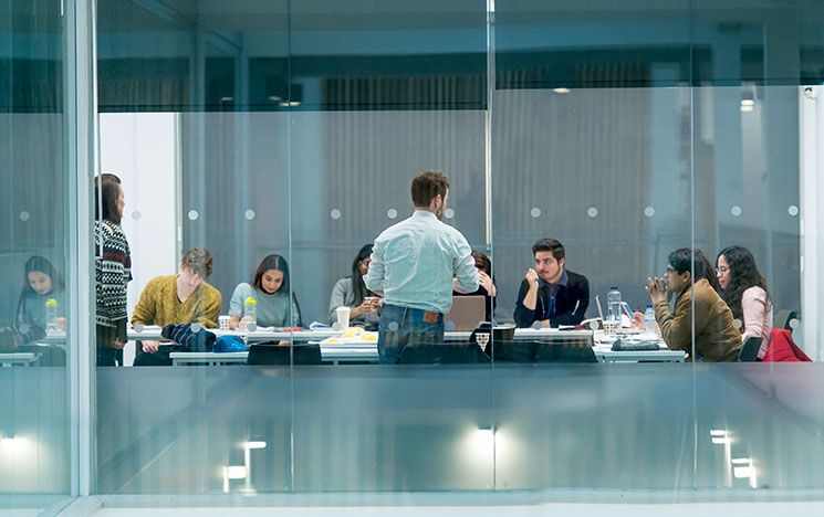 Students working, with a large map on the wall behind them