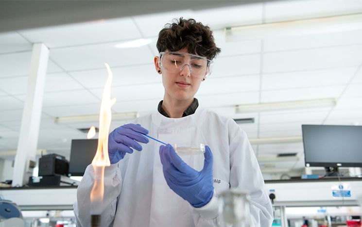 Biology student doing experiments in one of Sussex's laboratories, working with a Bunsen burner