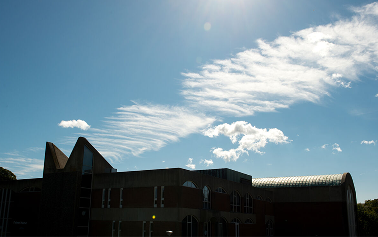 A campus building in shadow against a bright blue sky