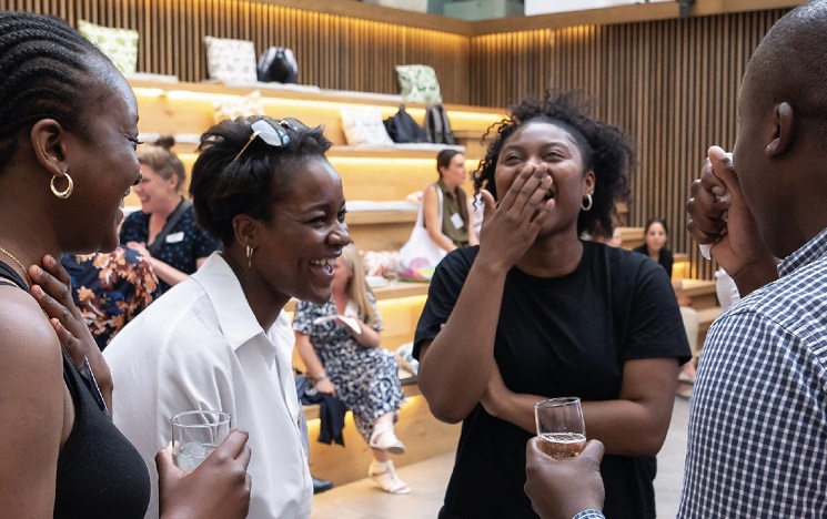 4 people holding drinks and laughing